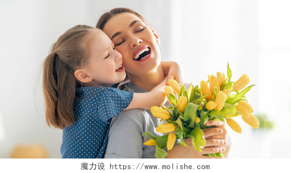 送给妈妈花朵的女儿抱着妈妈母亲节快乐。小女儿向妈妈表示祝贺,并送给她鲜花.妈妈和女孩笑着和拥抱。家庭假日和团聚.